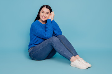 Full size profile side photo of young attractive lovely pretty girl sitting on floor isolated over blue color background