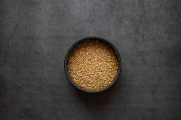 Oats rice in bowl on dark grey background.