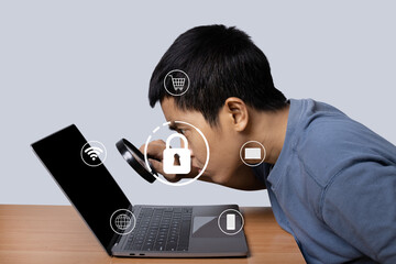 Young man observing laptop with magnifying glass with lock icon security technology.