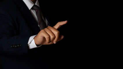 Young businessman pointing finger touching on screen black background.