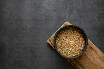 Oats rice in bowl on dark grey background.
