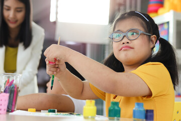 Happy children having fun with friends during study at school, girl with down syndrome concentrate...