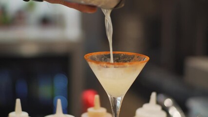 A male's hand pouring martini drinks into the glass in 4K