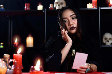Mysterious magnificent beautiful woman fortune teller in black hood read future on card and call to...