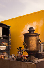 Old antique golden samovar. Vintage. White smoke, yellow wall. Drink tea