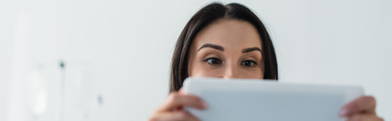 brunette patient covering face while using digital tablet in hospital, banner