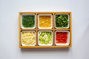 Chopped Fresh Coriander leaves and Green onion and Ginger and Chili pepper and garlic in white plate on white background. top view.