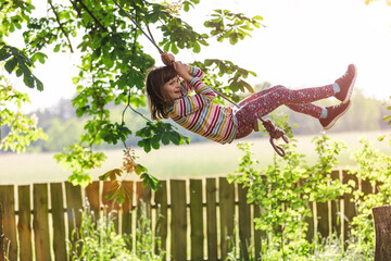 Happy girl on a tree swing in the garden
