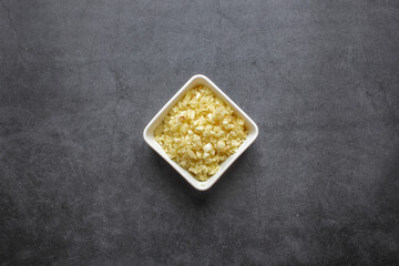 Chopped garlic in white plate on dark grey background. top view.