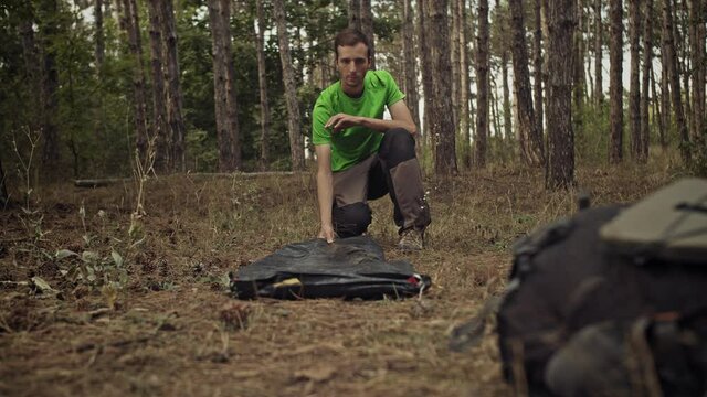 Survivalist in the forest sets up a tent. Gloomy Forest