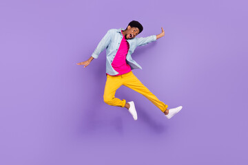 Fototapeta na wymiar Photo of sportive crazy carefree guy jump excited face wear blue shirt pants sneakers isolated purple color background