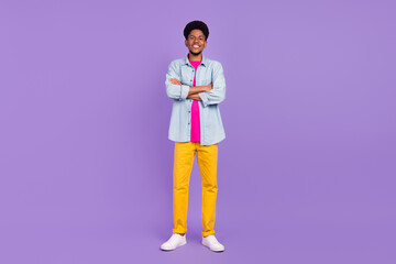 Photo of pretty confident dark skin guy dressed jeans shirt arms crosses smiling isolated violet color background