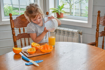 the child girl in the kitchen cuts and squeezes oranges juice