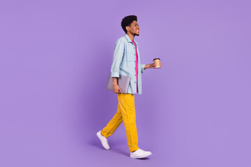 Photo of funky cute man wear denim walking drinking tea looking empty space holding gadget isolated purple color background