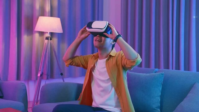 Young Asian Man Explores Virtual Reality At Living Room, Cyan And Magenta Colors
