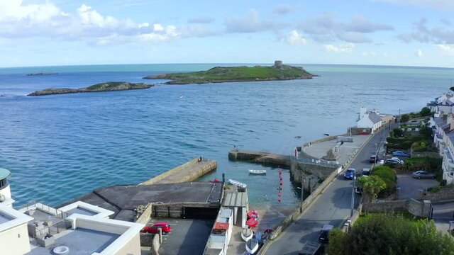 Coliemore Harbour, Dalkey, Dublin, Ireland, September 2021. Drone gradually orbits from the west revealing the view east to Dalkey Island while people swim and fish.