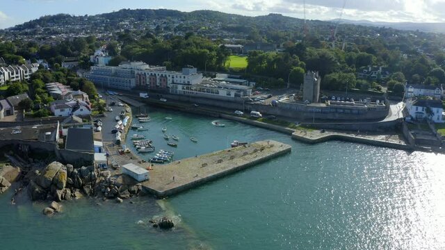 Bullock Harbour, Dalkey, Dublin, Ireland, September 2021. Drone tracks along the north quay as a boat circles in the habour with views south towards Killiney Hill.