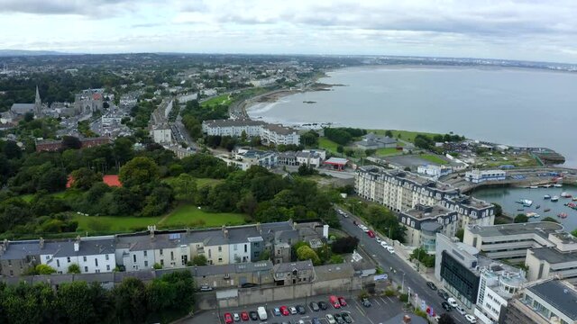 Monkstown, Dublin, Ireland, September 2021. Drone gradually pushes west along the coastline towards Monkstown Crescent with views towards the city center with Poolbeg Power Station in the distance.