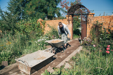 A man unloads sand into a cement mixture for pouring a garden path