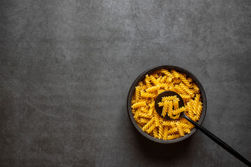 Spiral macaroni on dark grey background.