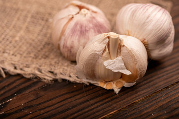 Heads of young garlic on a table covered with burlap, close-up, selective focus.