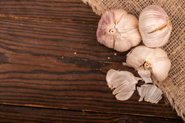 Heads of young garlic on a table covered with burlap, close-up, selective focus.