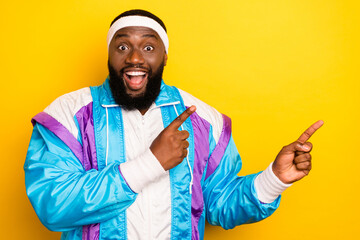 Photo of sweet excited dark skin man wear blue suit headband pointing fingers empty space smiling isolated yellow color background