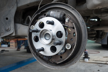 Auto mechanic repairing bearings and replacing car brake pads.