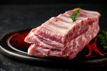 Raw pork ribs with spices and thyme on a dark wooden background
