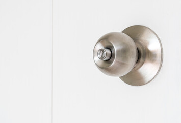 Silver color metal door knob on the white door. locked mode. copy space for text.