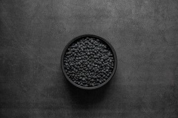 Black beans in bowl on black background.