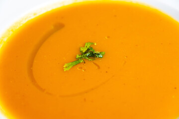 Fresh homemade pumpkins and carrots soup served in a pink bowl ready to be eaten