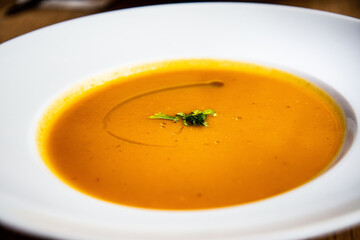 Fresh homemade pumpkins and carrots soup served in a pink bowl ready to be eaten