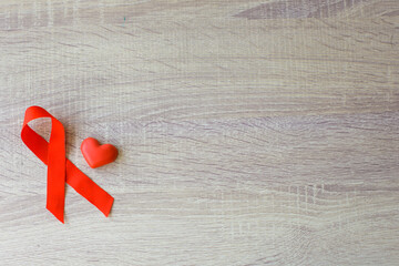 Red ribbon Hiv AIDS and heart shape for blood symbol on wooden background. World Aids day
