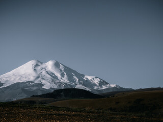 Mount Elbrus, night landscape. View of the highest mountain of the Caucasian ridge - Elbrus. Elbrus with two peaks against the background of a clear sky, the mountain is covered with snow. Copy space.