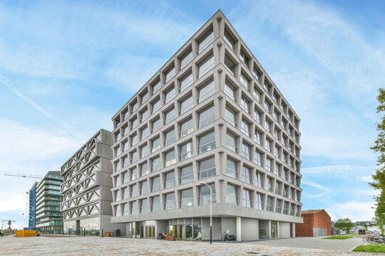 Contemporary building facades against urban pavements under cloudy sky