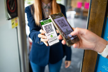 A young woman shows a digital covid passport when entering a restaurant.Responsibility above all.