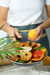 Woman in apron holds pan with grilled fruits