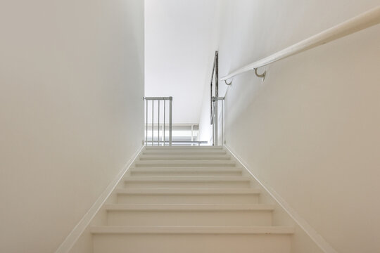 Modern empty stairs between walls with handrail