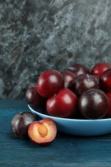 Blue bowl with plums on a blue wooden table