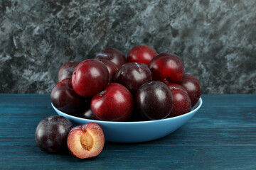 Blue bowl with plums on a blue wooden table