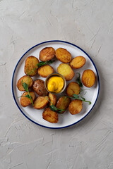 Top view of a tray of roasted baby potato with a portion of cheese sauce in the centre