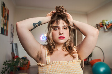 Woman with vivid makeup and unshaven armpits touching her hair