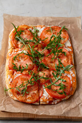 Hot pepperoni pinsa on thin crust, top view on grey stone background, copy space