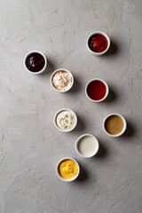 A lot of different sauces and dips on stone grey background, fashionable ad photo