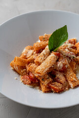 Meat pasta with small cherry tomatoes, appetizing view for a menu, wide grey plate, cold colors