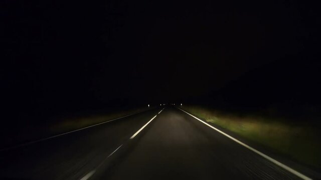 point of view hyper lapse of driving along Iceland roads at night. the car is speeding along highway with the headlights being the only way making the road visible  
