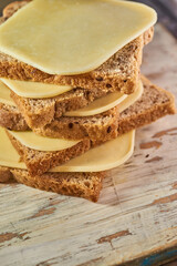 Sliced pieces of cheese on rustic wooden background, cheese sandwiches