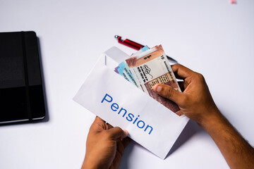 Shoulder shot of man opening received pension money from envelope - concept of retirement pension...