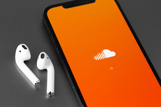 Soundcloud logo mobile app on screen smartphone iPhone with AirPods headphones closeup. SoundCloud is a global online audio distribution platform. Moscow, Russia - June 10, 2021